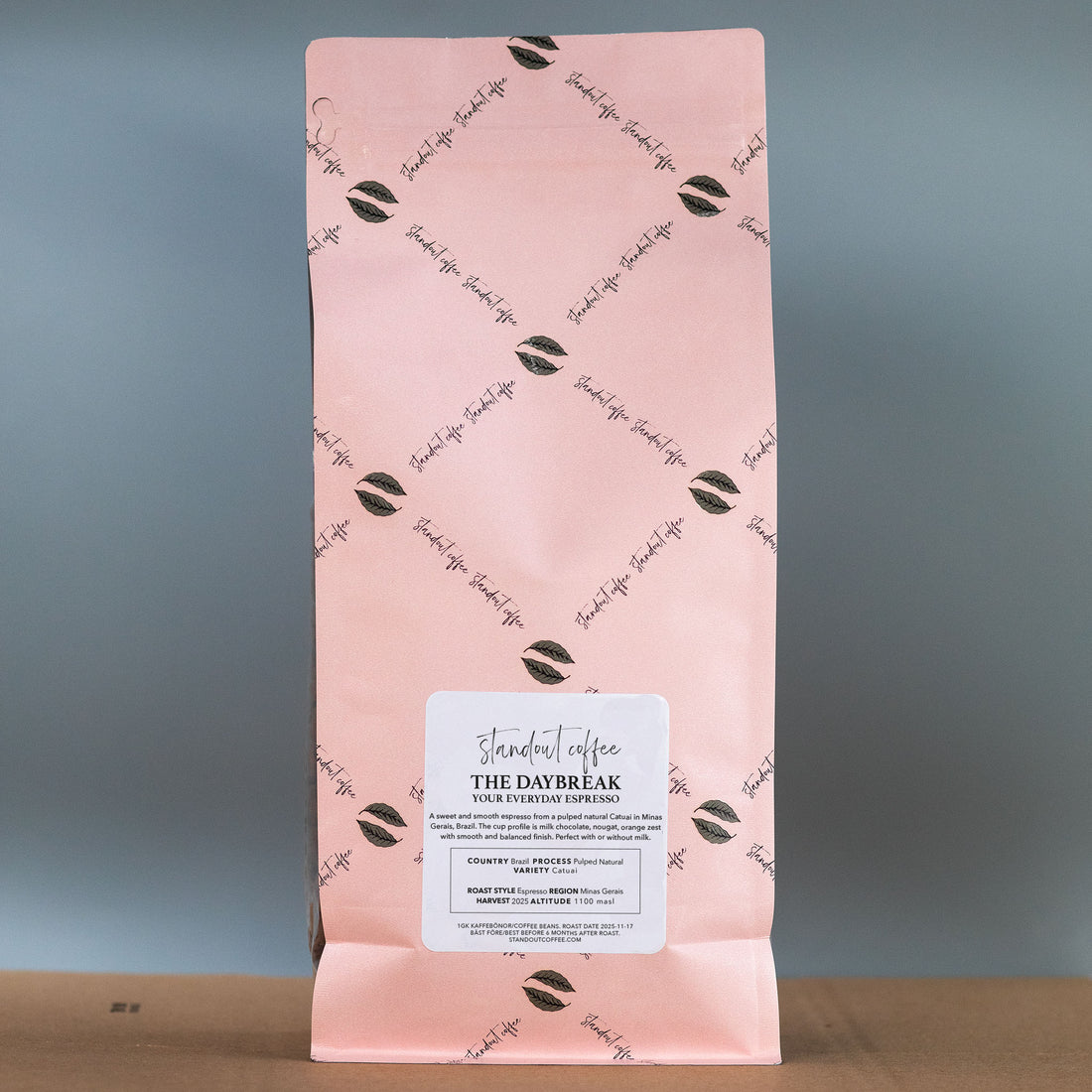 Pink coffee bag with brand logo and text on a gray background